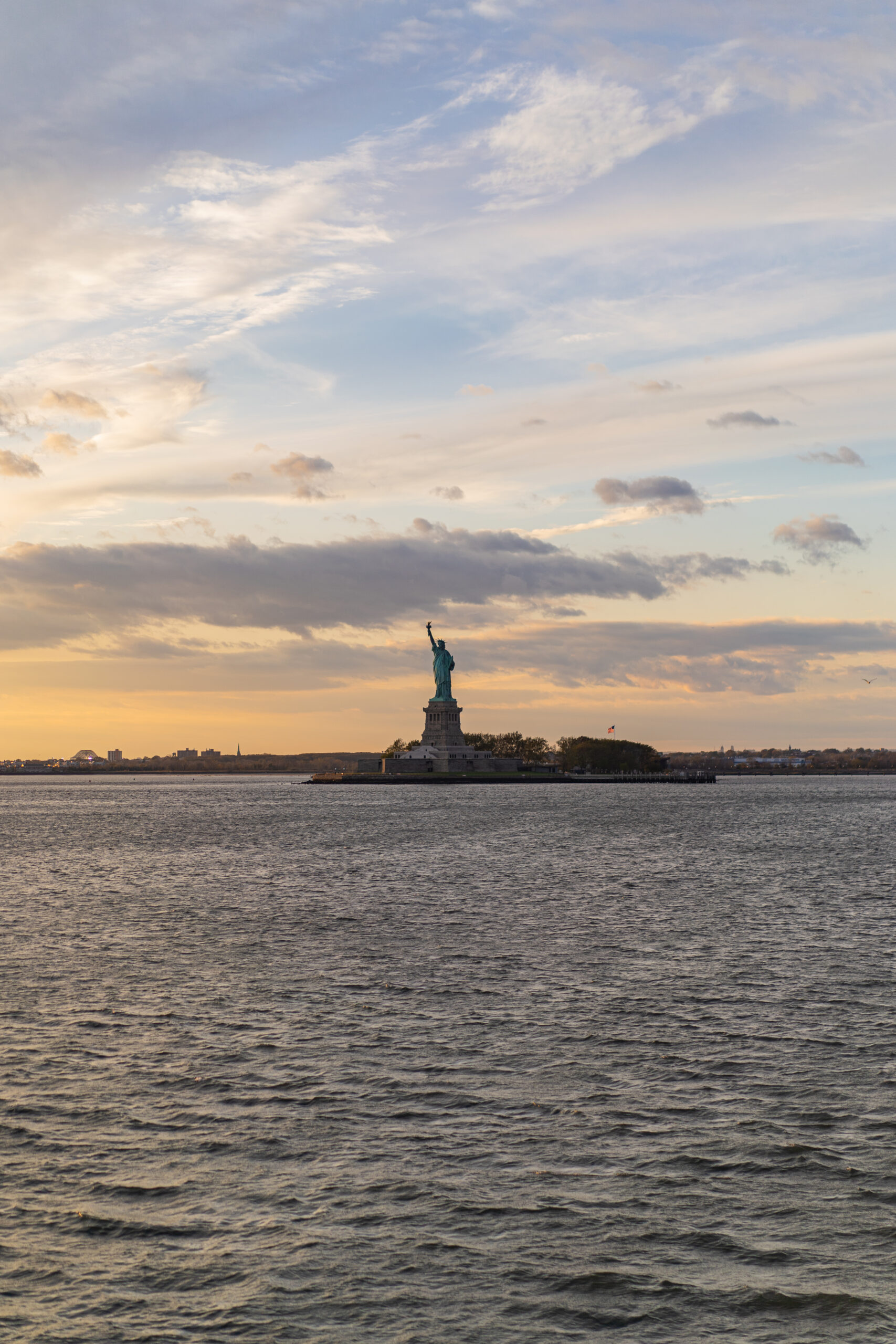View of the Statue of Liberty from the water at sunset in New York Harbor
