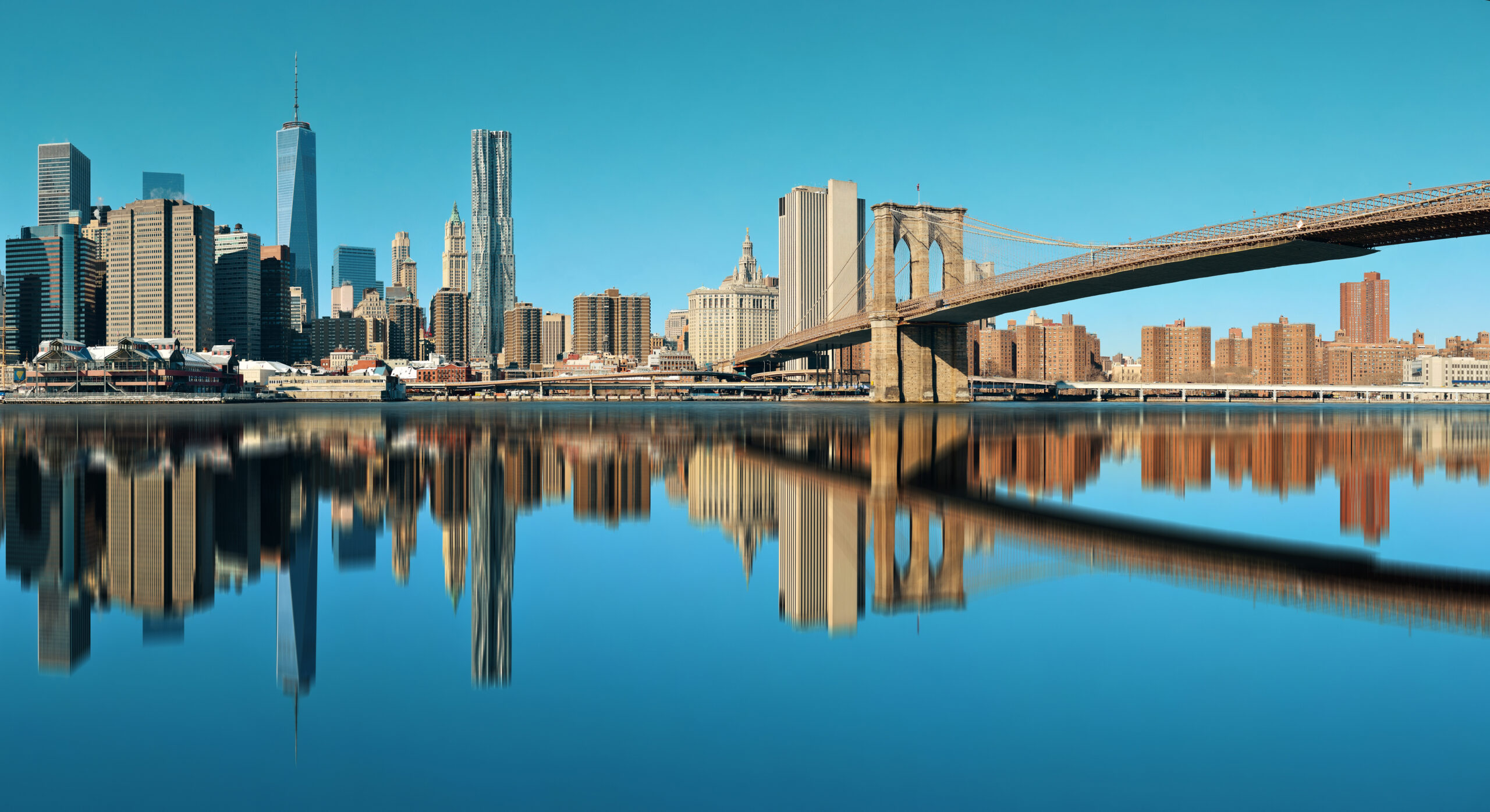 Manhattan skyline and Brooklyn Bridge reflected in the water