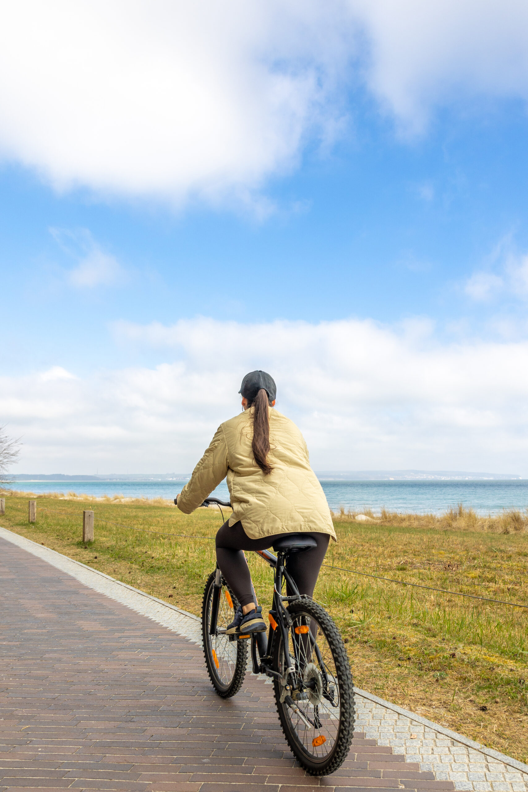 Woman cycling toward the sea on a California coastal bike path near Santa Monica