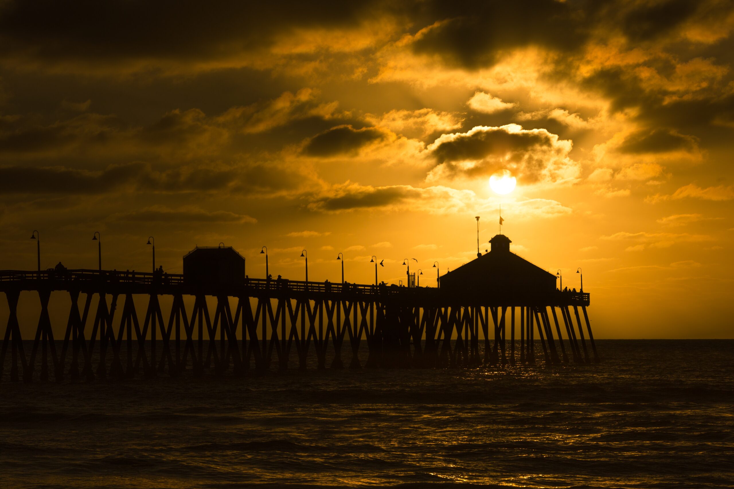 Beautiful sunset at a pier with dramatic cloudy sky reflecting on water near Santa Monica